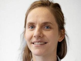 A woman wearing glasses and a pink shirt.