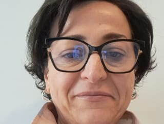 A woman wearing glasses and a pink shirt.