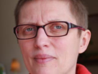 A person with short hair and glasses looking at the camera. Ann Tanghe